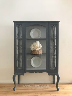 a black china cabinet with plates and flowers on it