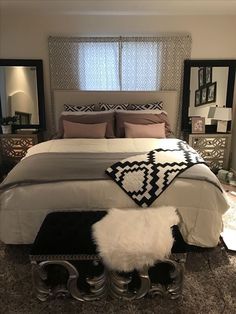 a bedroom with a large bed and mirror on the wall above it is decorated in black and white