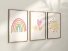 three framed pictures hang on the wall in a room with sun, rainbow and heart shapes