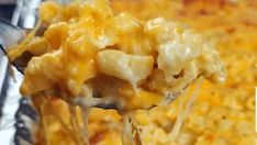 a spoon full of macaroni and cheese being lifted from a casserole dish