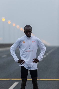 a man standing in the middle of an empty road with his hands on his hips