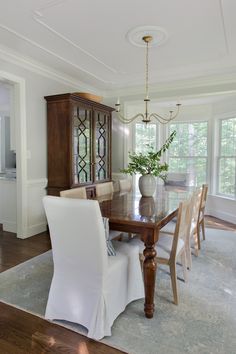 a dinning room table with white chairs and a vase on top of the table