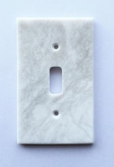 a white marble light switch plate on a blue background with one hole in the middle