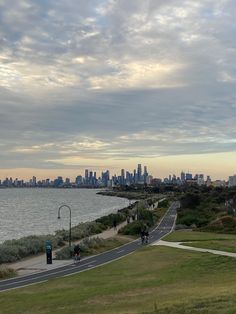 a view of the city skyline from across the water with people walking on the sidewalk