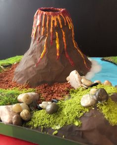 a cake made to look like a volcano with rocks and grass on it's sides