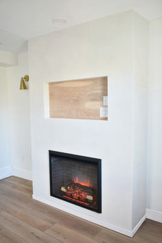 a fire place in a room with wood flooring and white paint on the walls