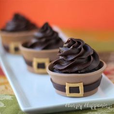 three cupcakes with chocolate frosting on a white plate and green tablecloth