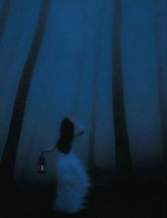 a person standing in the dark with a lantern on their head and trees behind them