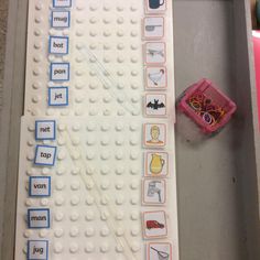 a lego board with words and pictures on it next to a pink toy box filled with toys