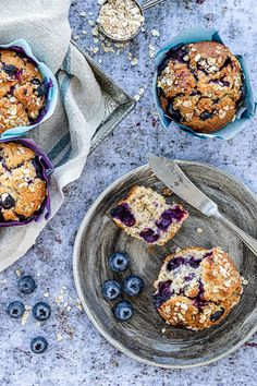 two blueberry muffins on a plate with one cut in half