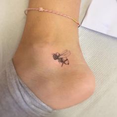 a woman's foot with a small tattoo of a bee on the side of her ankle