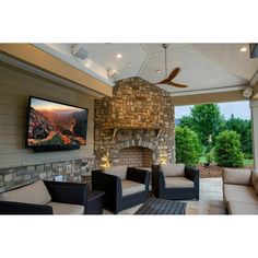 an outdoor living area with furniture and a flat screen tv mounted on the wall above it