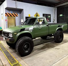 a green pick up truck parked in a garage