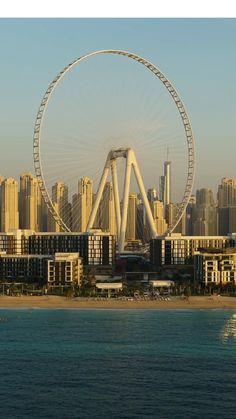 a large ferris wheel in front of a cityscape with tall buildings on the other side