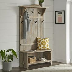 a wooden bench sitting next to a white wall with hooks on it's sides