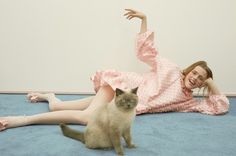 a woman in pink dress laying on the floor next to a cat