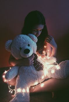 a woman holding a white teddy bear with lights on it's chest and arms