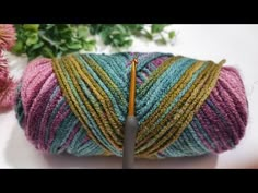 a ball of yarn with a crochet hook in front of it and flowers