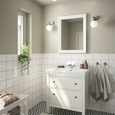 a white bathroom with black and white tile on the floor, sink, mirror and towel rack