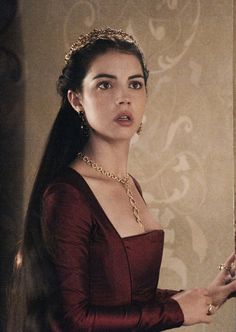 a woman with long hair wearing a red dress and holding a gold chain around her neck