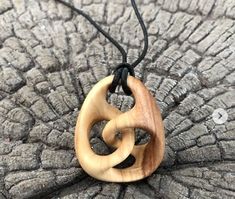 a wooden necklace with two interlocked circles hanging from a cord on top of a piece of wood