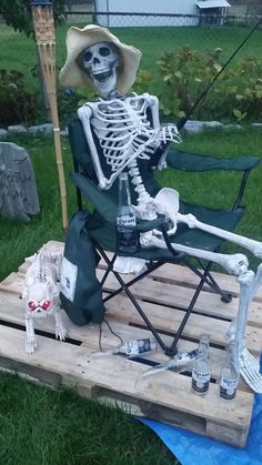 a skeleton sitting in a lawn chair on top of a wooden pallet