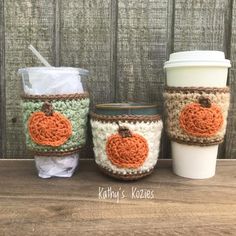 three coffee cups with pumpkins on them sitting next to each other and one cup has a straw in it