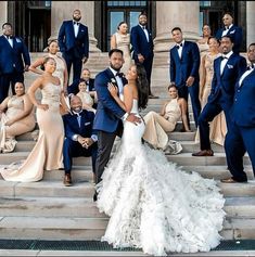 a group of people posing for a photo in front of some stairs with their wedding dresses on