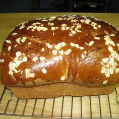 a loaf of bread sitting on top of a wire rack covered in oatmeal