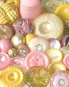 there are many different buttons on the table together, including one pink and one yellow