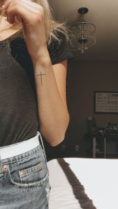 a woman with a cross tattoo on her left arm and right arm behind her head