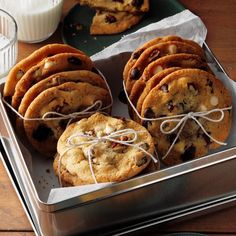 chocolate chip cookies and milk in a metal container on a wooden table with napkins