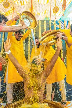 a group of men in yellow shirts splashing water on each other with their hands