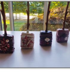 four small boxes are lined up on a table near a window with trees in the background