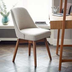 a chair sitting in front of a window next to a table with a plant on it