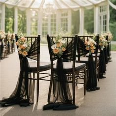 chairs with black sashes and flowers on them are lined up in front of a white tent