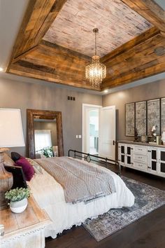 a bed room with a neatly made bed and a chandelier hanging from the ceiling