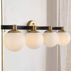 three lights are hanging on the wall next to a mirror and curtain in front of a window