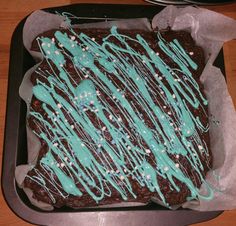 a chocolate cake with blue icing and white sprinkles