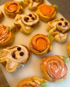 there are many small pastries on the table with orange icing and chocolate chips