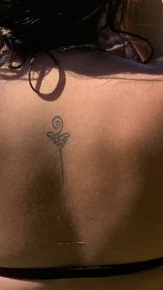 the back of a woman's body with a tattoo on her lower back and neck