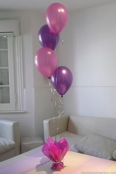 a bunch of balloons that are sitting on a table in front of a couch and window