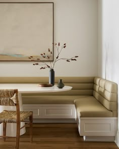 a white table and bench in a room with a painting on the wall behind it