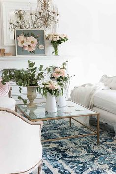 a living room filled with furniture and flowers on top of a glass topped coffee table