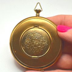 a person holding an antique pocket watch in their hand with pink nail polish on it