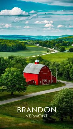 a red barn sits in the middle of a green field