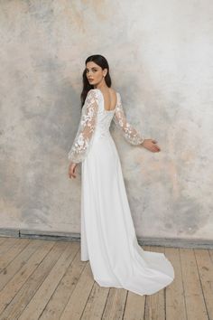 a woman in a white wedding dress standing on a wooden floor with her arms outstretched