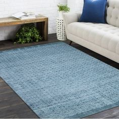 a living room with a white couch and blue rug