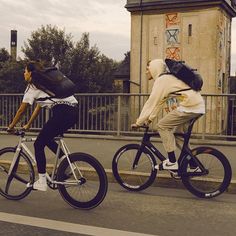 two people riding bikes down the street