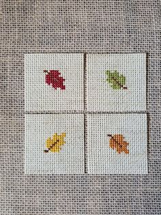 four cross stitch coasters with leaves on them